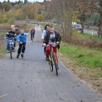 Ścieżka rowerowa w gminie Słupsk. Dzieci jadą na rowerach i na rolkach.