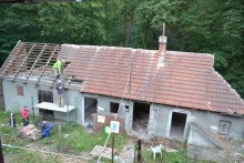 Rozbiórka budynku -widok na częściowo rozebranym stary budynek z pustaków z dachem z wyblakłej, czerwonej dachówki